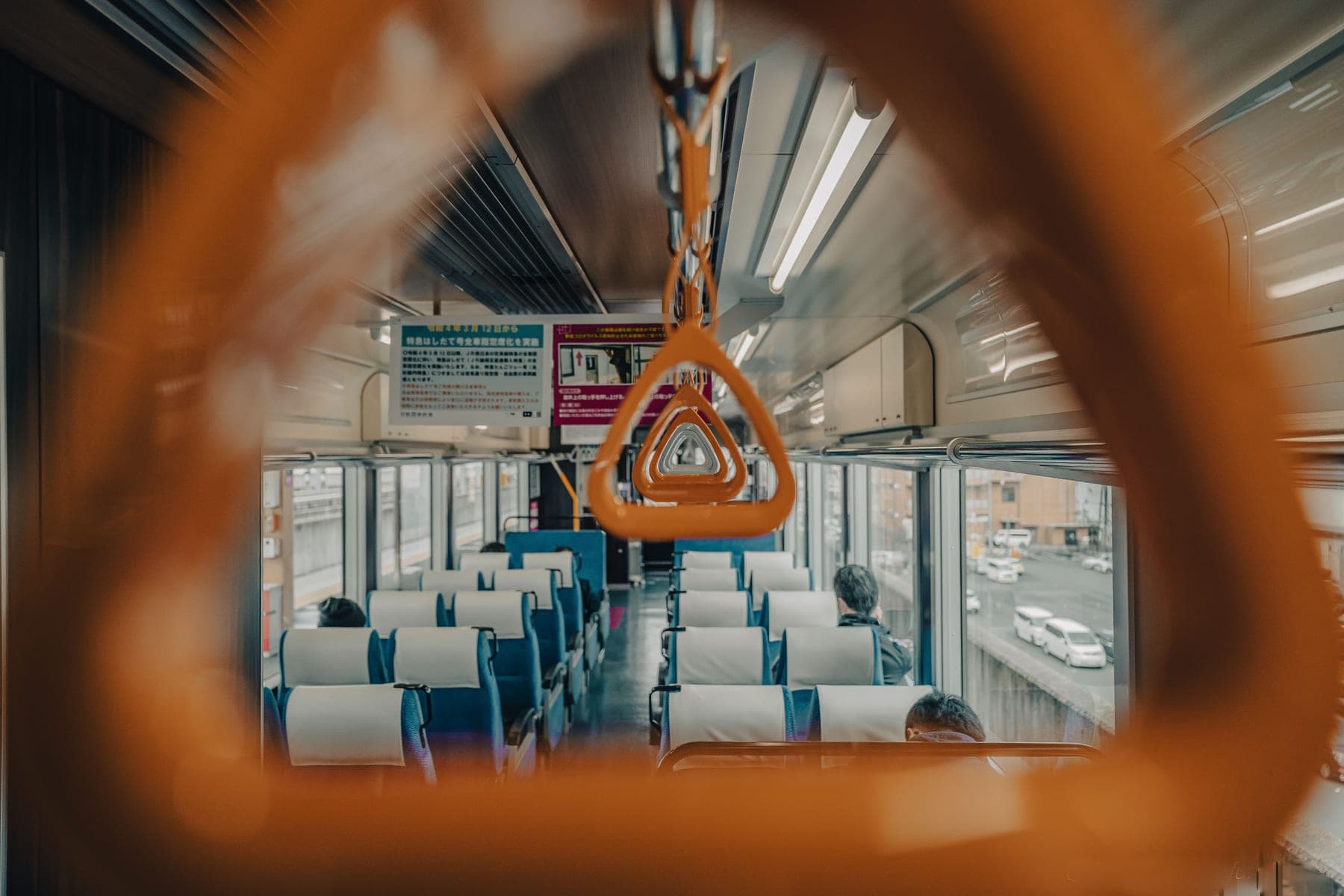 Interior of a modern train carriage with empty seats and handrails