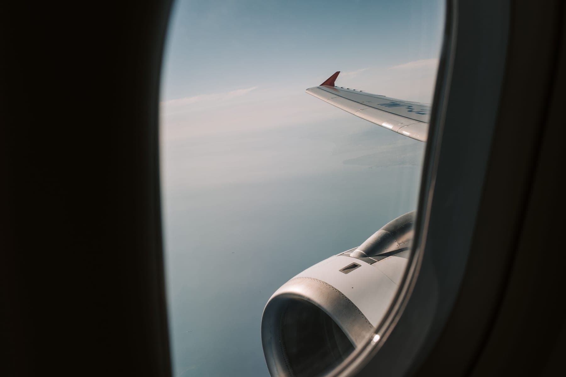 View of an airplane wing and engine at altitude through a passenger window